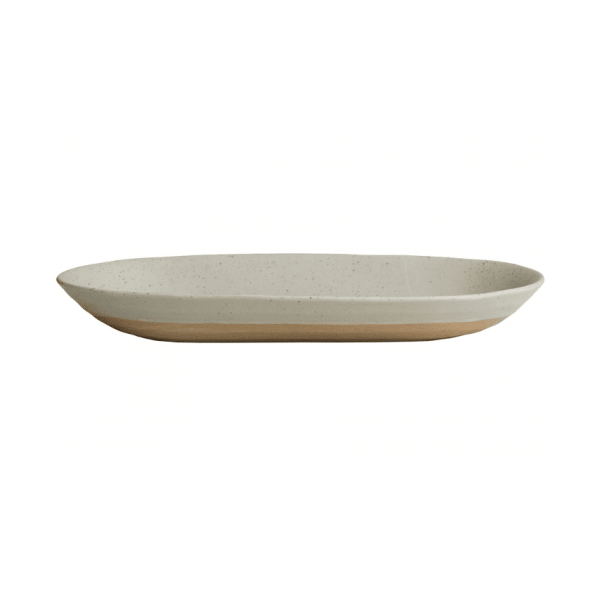En keramisk oval tallerken med en plettet beige glasur, med en let hævet kant, vist mod en almindelig hvid baggrund. NORDAL - Kornet Serveringsfad.