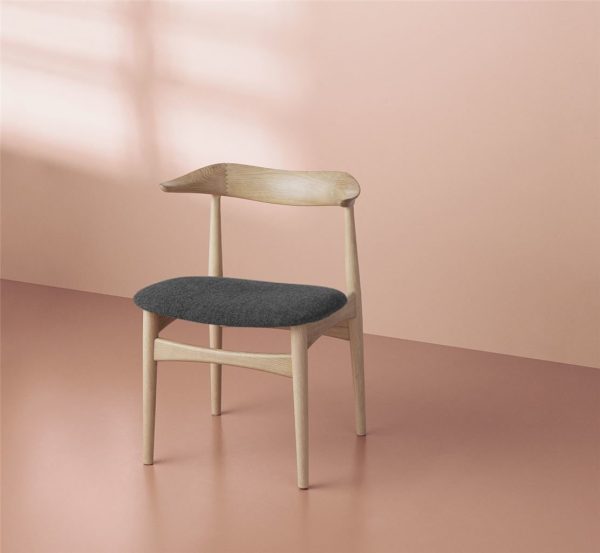 En minimalistisk træstol med et buet ryglæn og et mørkegrå polstret sæde, sat mod en blød pink baggrund, viser essensen af TomorrowsDesign.