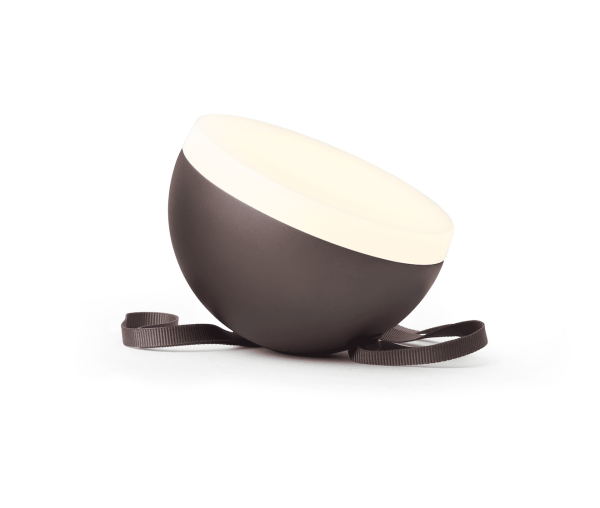En skrå brun NEW WORKS - Sphere Adventure Lampe med cremefarvet interiør og brun rem, isoleret på en hvid baggrund.