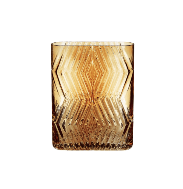 En HÜBSCH - Ivy Vase med indviklede geometriske designs, fyldt med ravfarvet væske, sat mod en hvid baggrund. krystalfacetterne bryder lyset og forstærker glassets gnistre.