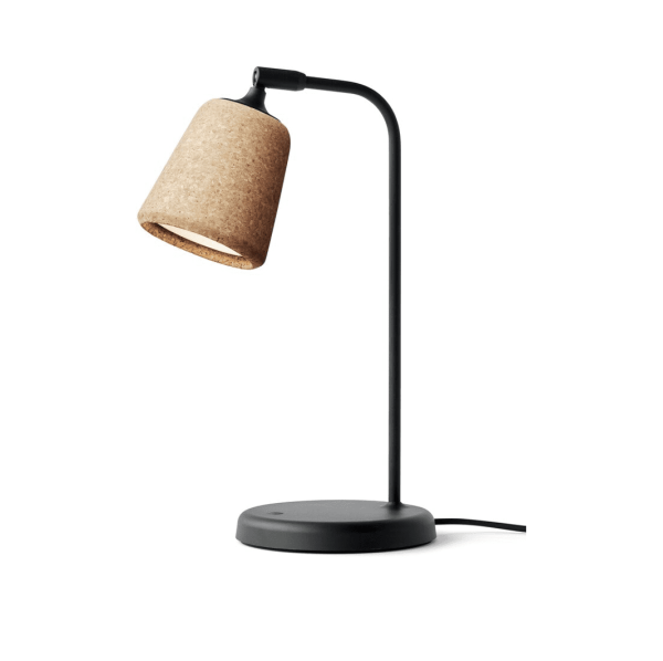 En moderne skrivebordslampe med en sort buet stander og en cylindrisk kork lampeskærm, sat mod en almindelig hvid baggrund. NYHED - Materiale Bordlampe.