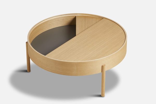 Et moderne rundt sofabord i træ med en designer drejelig top halvåbnet, der afslører et skjult opbevaringsrum, sat mod en hvid baggrund.