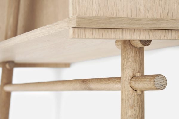 Nærbillede af en WOUD - Töjbox Garderobe-samling, der viser et lyst egetræ med finkornet tekstur, med en stift- og tapsamling i interiørdesign.