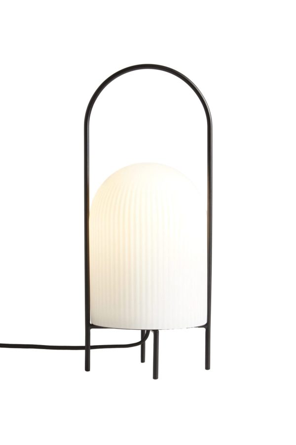 En WOUD - Ghost Bordlampe med en ribbet hvid globeskærm og en elegant sort metalramme buet over den, isoleret på en hvid baggrund, designet af Tomorrowsdesign.