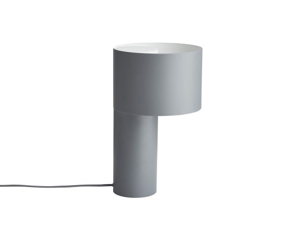 En moderne grå cylinder bordlampe fra Tomorrowsdesign, med en øvre skærm, der dækker halvdelen af pæren, placeret mod en hvid baggrund, med en synlig sort strømledning.