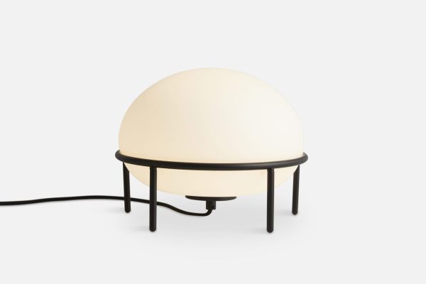 A WOUD - Pump Bordlampe med en glødende hvid sfærisk skærm sat på en minimalistisk sort metalramme, isoleret mod en almindelig hvid baggrund fra Tomorrowsdesign.