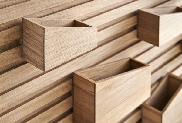 Nærbillede af en trævæg med fremspringende rektangulære skuffeelementer, der viser en moderne og minimalistisk *designermøbel* æstetik med fokus på rene linjer og funktionel opbevaring.