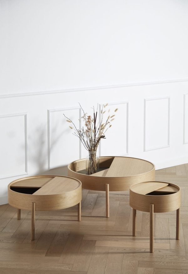 Tre moderne WOUD - Arc Sidebord Ø42 indskudsborde i varierende størrelser, placeret på et hårdttræsgulv mod en hvid panelvæg. Det største bord, et designerstykke fra Tomorrowsdesign, rummer en vase med tørrede planter.