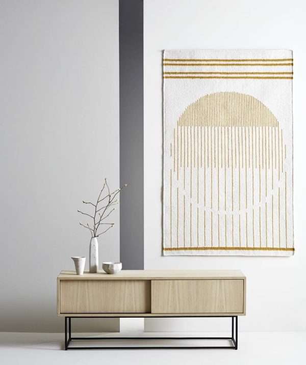 Et minimalistisk interiør med et konsolbord i træ med to keramiske vaser og en gren. Et vægtapet med geometriske mønstre hænger ovenover i et neutralt tonet rum med designermøbler.