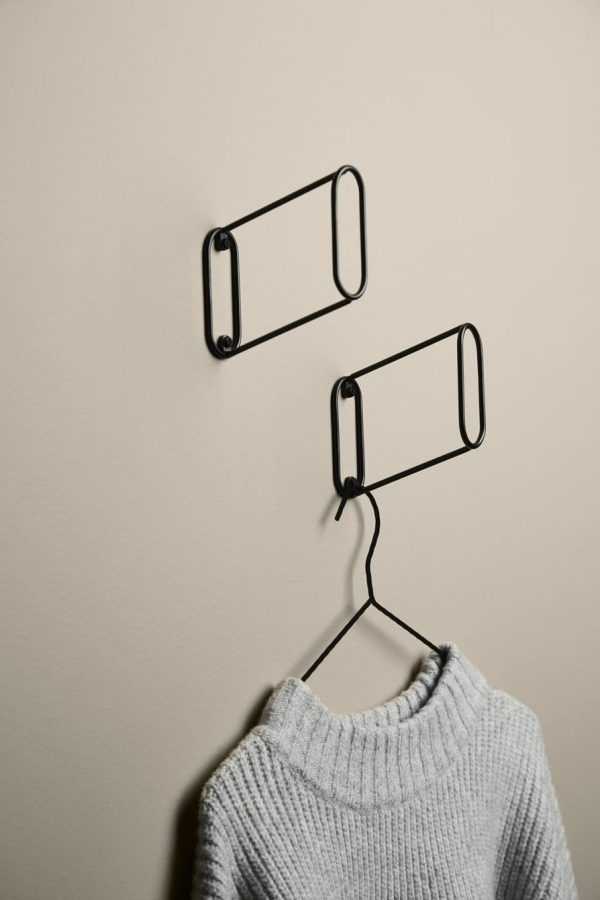 En cremefarvet væg med to sorte rektangulære trådrammer monteret, den ene nederste ramme holder en grå striktrøje på en bøjle, eksemplificerer Tomorrowsdesign.