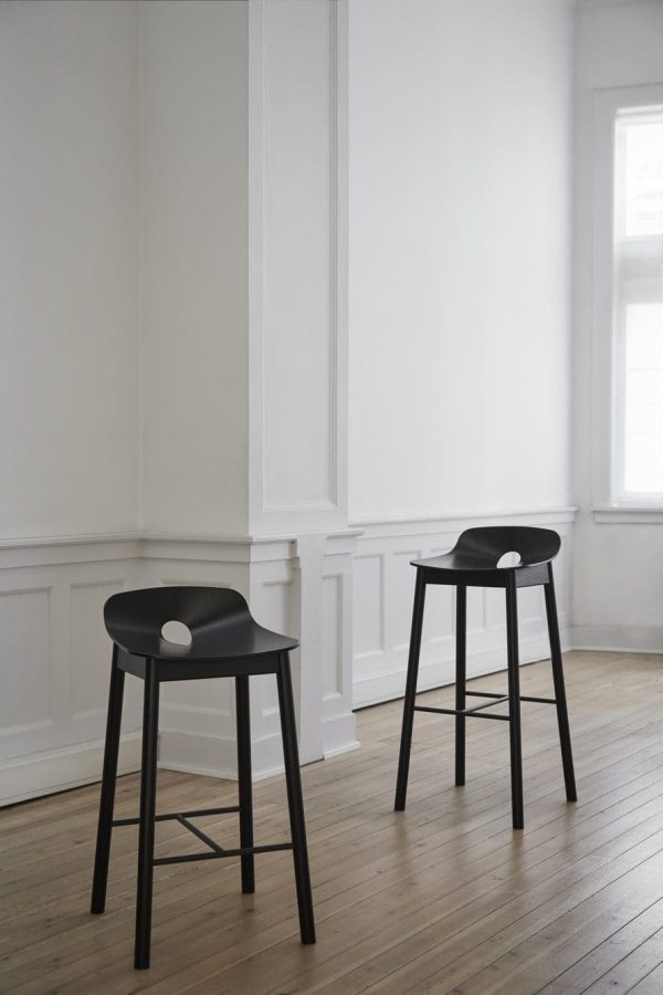 To sorte moderne taburetter i et hvidt, minimalistisk rum med trægulve, naturligt lys fra et vindue og elegant designermøbel vægbeklædning.