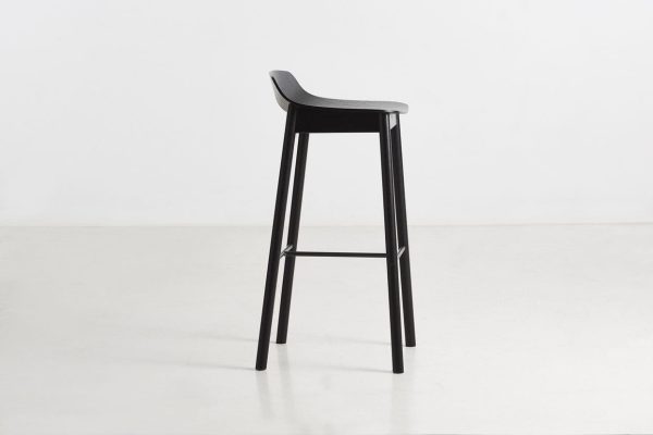 En moderne sort barstol med en elegant designermøbel, med buet sæde og slanke ben mod en hvid baggrund.