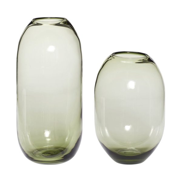 To høje, gennemsigtige grønne glasvaser i forskellige størrelser, side om side på hvid baggrund. Vaserne er glatte med en cylindrisk form, let tilspidsende mod bunden, indbegrebet