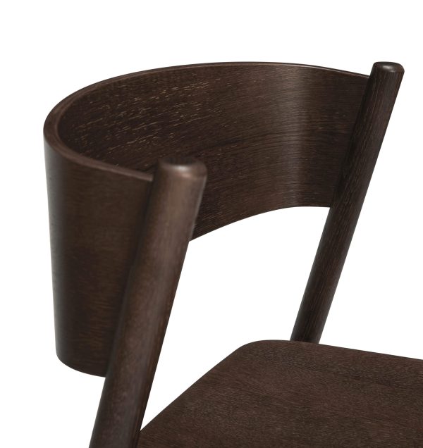 Nærbillede af en mørk træstol med fokus på det buede ryglæn og en del af sædet, der viser den glatte træåre og det elegante designermøbeldesign.