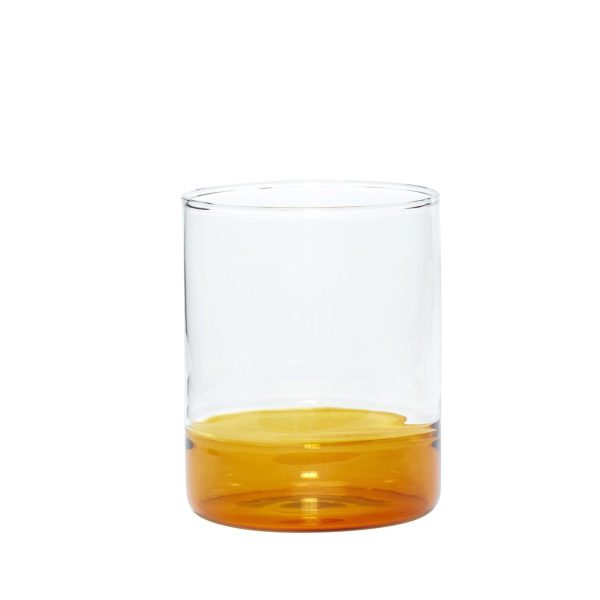 Et klart HÜBSCH - Kiosk Drikkeglas med en lille mængde ravfarvet væske, eventuelt whisky eller æblejuice, siddende på en almindelig hvid baggrund.