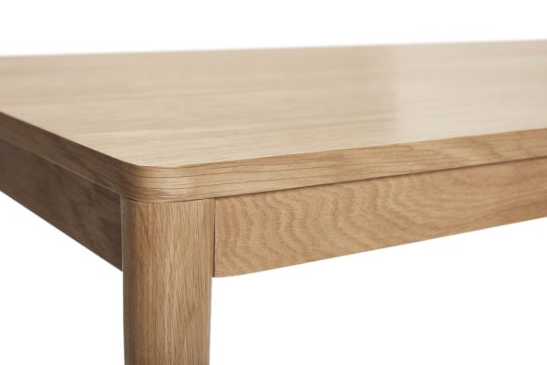 Nærbillede af et hjørne af et træbord, der viser den glatte overflade og detaljerede træårer, perfekt til Tomorrowsdesign-entusiaster, med bordbenet let synligt.