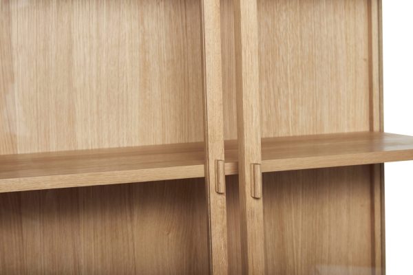 Nærbillede af et træskab, der viser detaljerne i dets lysebrune hylder og det enkle design af dets lodrette skillevæg, der perfekt inkarnerer interiørets etos.