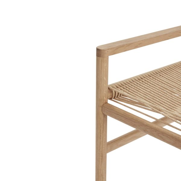 Nærbillede af en designer træstol med beige vævet sæde, der viser teksturen og designet af håndværket, mod en hvid baggrund.