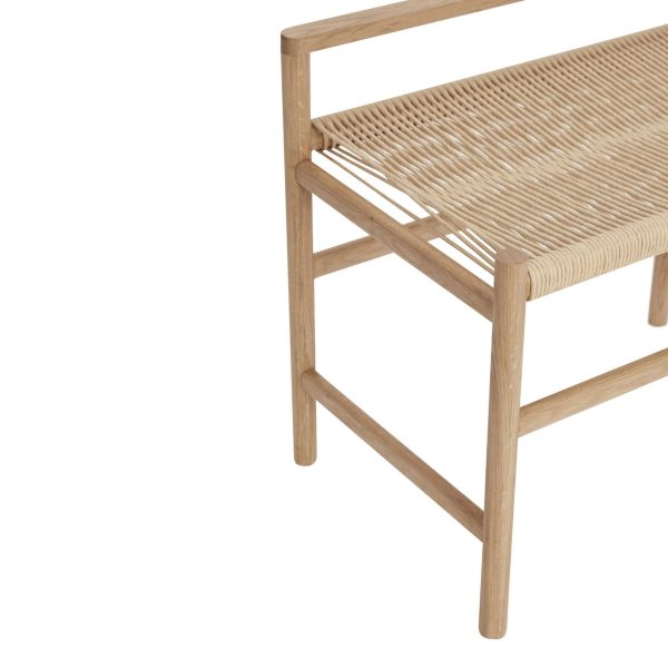 Set fra siden af en minimalistisk træstol med vævet rattansæde og ryglæn. Stolen har et enkelt, rent design med lodrette stelstøtter. En hvid baggrund forbedrer synet af de naturlige teksturer og
