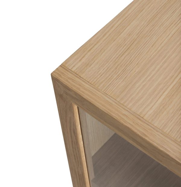 Nærbillede af et lys skabshjørne i træ med et klart glaspanel, der viser træets naturlige årring og glatte finish mod en hvid baggrund, som eksemplificerer Tomorrowsdesigns håndværk.