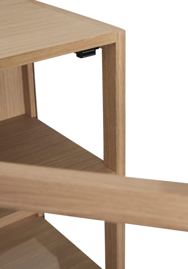 Nærbillede af et skrivebordshjørne af træ, der viser detaljer af tekstur og design, med fokus på krydset, hvor den øverste overflade møder sidepanelet. En sort skuffeslide er delvist synlig under bordpladen.