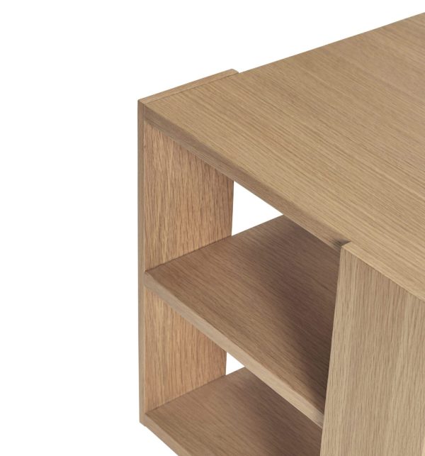 Nærbillede af et moderne træskrivebord med minimalistisk design, der viser et sidebillede med et lille hylderum. Træet har en let, naturlig finish med synlige åremønstre.