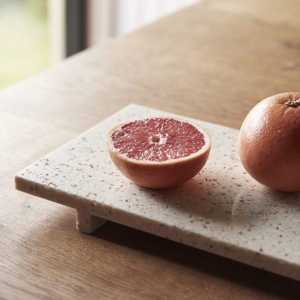 Halvt og hel HÜBSCH - Stone Bakke Terrazzo på et træbord, der viser et nærbillede med naturligt lys.