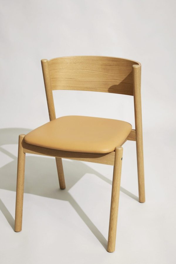 En moderne træstol med buet ryglæn og et solbrunt polstret sæde fra Tomorrowsdesign, sat mod en almindelig, lysegrå baggrund.