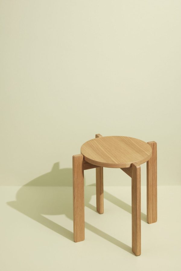 En lille, rund HÜBSCH - Always Taburet med fire ben, fremvist mod en lys beige baggrund med en subtil skyggekast til venstre. Den overordnede tone og belysning giver den et rent og minimalistisk udseende.