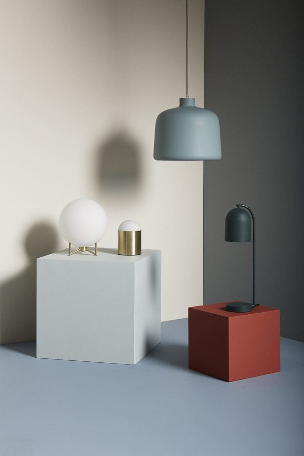 Et moderne stilleben med stilfulde lamper på geometriske blokke, med et slankt, vinklet lys, der kaster skygger på en tofarvet baggrund, der afspejler essensen af Tomorrowsdesign.
