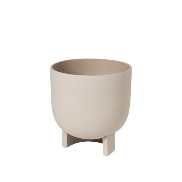En beige keramisk plantekasse med et minimalistisk design, med en glat, afrundet krop og tre små ben til støtte, isoleret på en hvid baggrund.