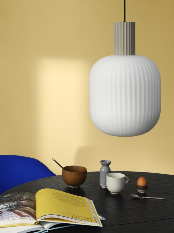 En moderne spisestue med et sort rundt bord med en blå stol fra TomorrowsDesign. På bordet er der en skål med spisepinde, en flødekande, et æg i en holder