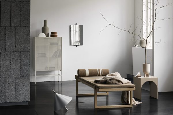 En minimalistisk stue med en træbænk, hvide hylder, dekorative vaser og dæmpede jordfarver, suppleret med en grå væg og hvidt gulv. Naturligt lys oplyser rummet med designm