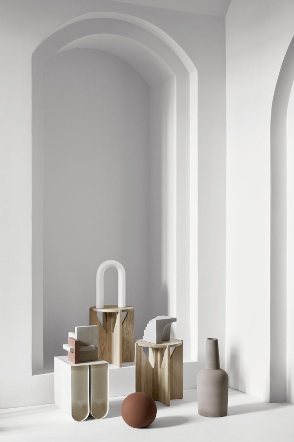 Et minimalistisk interiør med rolige omgivelser med elegante buede alkover mod en lysegrå baggrund. Scenen inkluderer et arrangement af moderne dekorative genstande i dæmpede toner og forskellige former, der perfekt inkarnerer det æstetiske