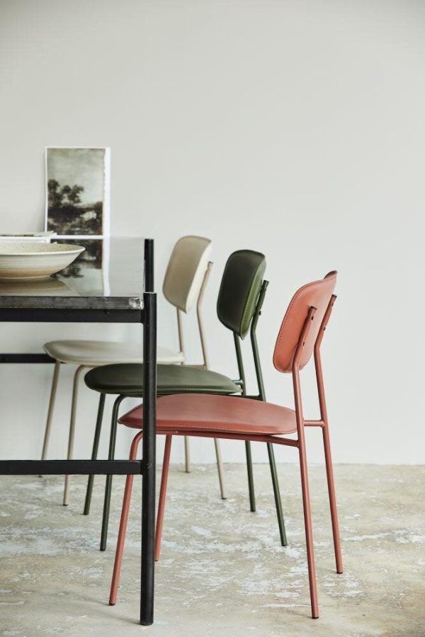 Fire moderne stole i forskellige nuancer af brun, creme og grøn stillet op mod et minimalistisk spisebord fra TomorrowsDesign med en refleksion af et maleri i et spejl over sig.