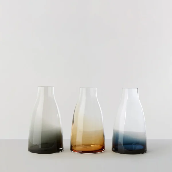 Three RO COLLECTION - Blomstervase nr. 3 med røgfyldte gradientdesign, der spænder i nuancer fra grå til rav til blå, vist mod en lysegrå baggrund.