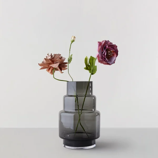 To blomster, en fersken og en lilla, elegant udstillet i en stablet, modulopbygget RO COLLECTION - Hurricane No. 69 vase på en almindelig hvid baggrund.
