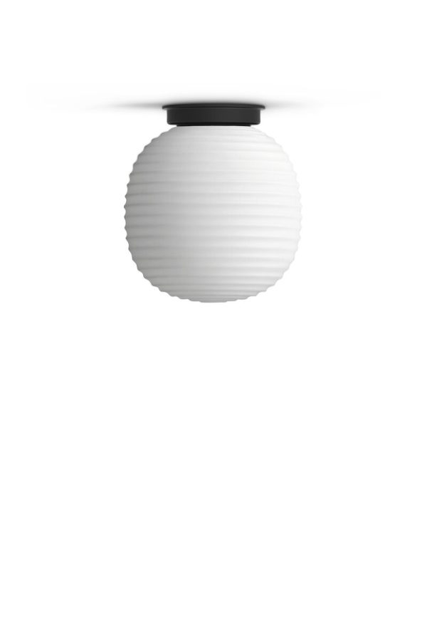 En moderne loftslampe med en globus af matteret glas og sort armatur, monteret på en hvid baggrund. NEW WORKS - Lantern Loftslampe Ø20 har en rillet tekstur, der forstærker dens æstetiske appel.