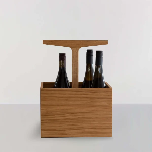 En vinbærer i træ med et håndtag, der rummer to flasker vin, udstillet på en almindelig lysegrå baggrund. Træet har en glat finish og en lysebrun farve. Dens elegante design passer til enhver