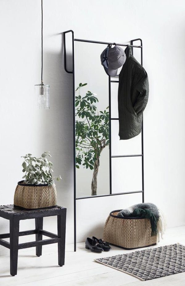 En minimalistisk entré med en knagerække i metal med en jakke og en hat, en vævet skammel, et pottetræ og sko placeret nedenunder har smart interiørdesign. Der medfølger også en pendel og et lille tæppe.