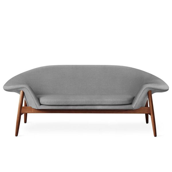 En moderne sofa med en glat, grå stofpude og en buet træramme, der skaber en slank, minimalistisk æstetik. Sofaen står på en almindelig hvid baggrund, hvilket understreger dens elegante designmøbler.