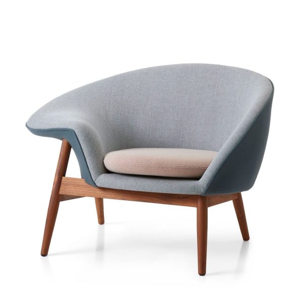En lænestol i moderne stil med træben og en buet lyseblå polstret krop på en almindelig hvid baggrund. Sædehynden er beige, i kontrast til Fried Egg Loungestols hovedfarve.