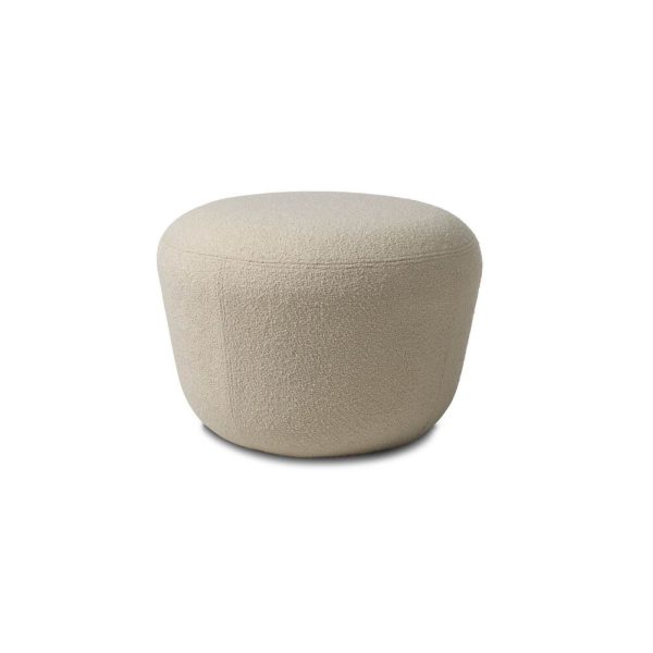 En enkel, lys beige Haven Puf skammel på en hvid baggrund, med et afrundet, polstret design med en tekstureret polstring.