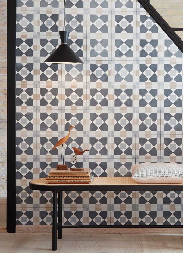 Et stilfuldt indvendigt hjørne med et geometrisk tapetdesign fra TomorrowsDesign, med et moderne træbord, en bænk toppet med en hvid pude og en elegant hængende sort lampe.