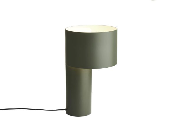 En moderne cylindrisk bordlampe med en matgrøn finish, med en sømløs øverste halvdel, der fungerer som lysspreder. Lampen er tændt, giver et blødt skær og inkluderer en synlig sort strømledning. Dens unikke design tilføjer et sofistikeret touch til ethvert interiør.