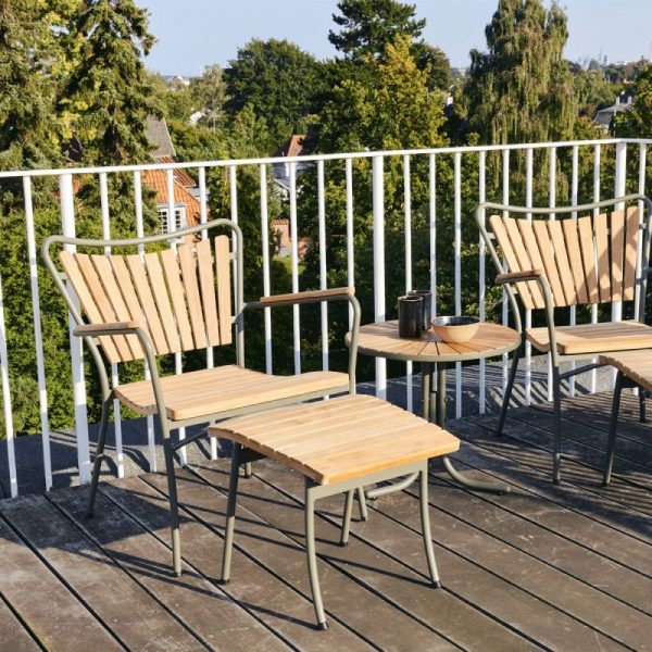 To træ- og metalstole med et matchende bord på en balkon med udsigt over et boligområde med træer, fremviser TomorrowsDesign. Et lille sort krus står på bordet. Omgivelserne er solrige med klar himmel.