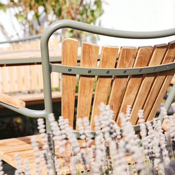 Nærbillede af en trælamelstol med metalramme på en balkon, omgivet af blomstrende lavendelplanter i blødt fokus, der perfekt fanger essensen af TomorrowsDesign.