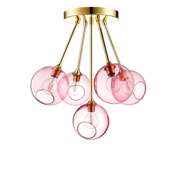 A DESIGN BY US - Ballroom Molecule lysekrone med fem lyserøde glaskugler hængende fra en guldbase, som hver indeholder en synlig glødetrådspære. designet kombinerer moderne og retro-elementer, og lægger vægt på transparent, varmfarvet glas.
