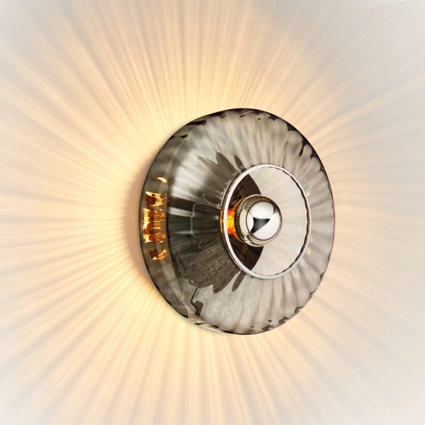 En rund loftslampe med et designinspireret metallisk center og et gennemsigtigt, tekstureret dæksel, der udstråler et varmt lys med striber af belysning, der strækker sig udad.