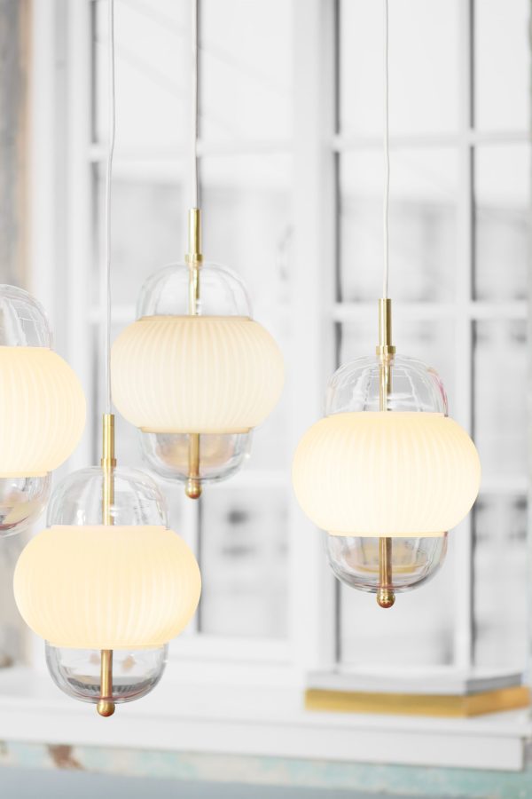 Design By Us - Shahin Pendel pendellamper med sfæriske, matterede glasskærme og guldaccenter, hængende foran et vindue med hvide rammer.